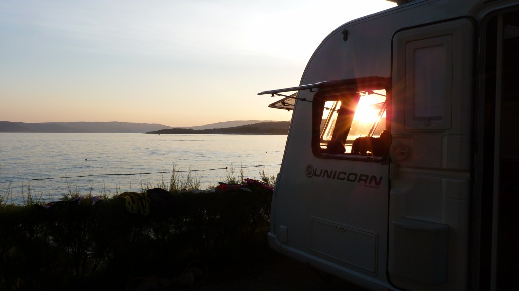 Front of caravan on ocean shoreline with sunset, just feet from the Adriatic on the Island of Krk, Croatia