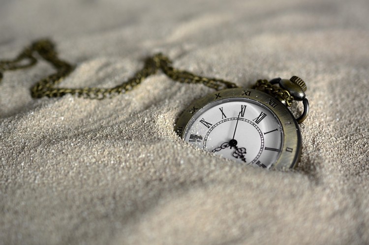 Pocket watch half buried in the sand to illustrate the quote from Fight Club movie "This is your life and it's ending one minute at a time.
