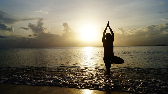Silhouette of a woman doing yoga tree position on a sunset beach