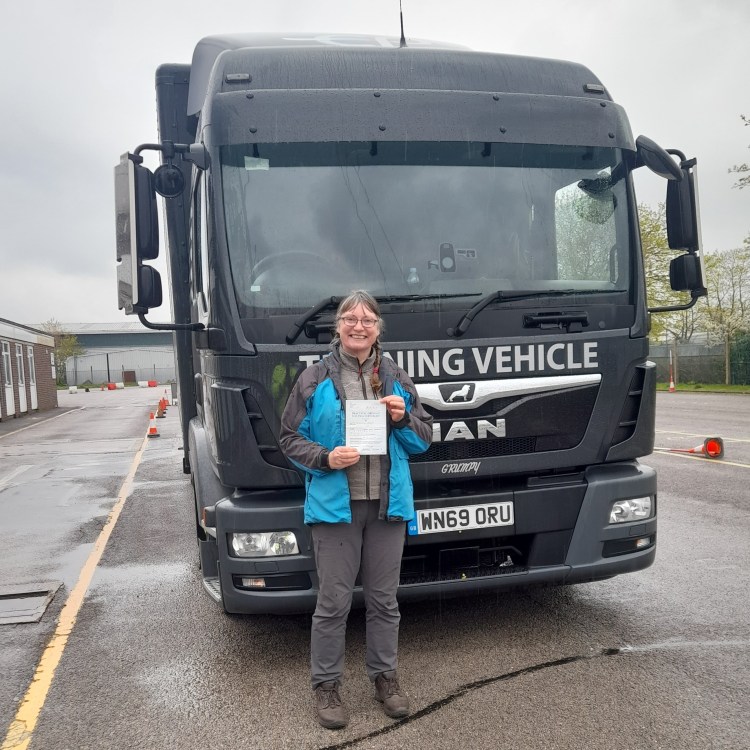 Jacqueline Lambert standing in front of a truck with her certificate after just passing her truck test