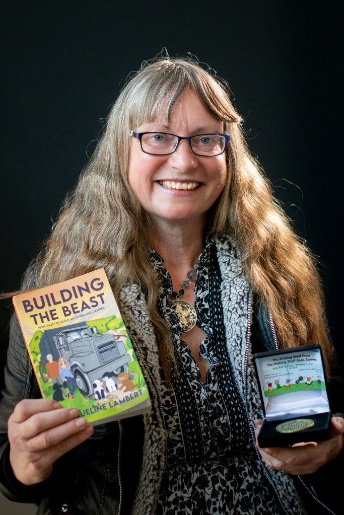 Hi Res photo of Author Jacqueline Lambert holding her multi award-winning book Building The Beast & her Wishing Shelf Book Award medal