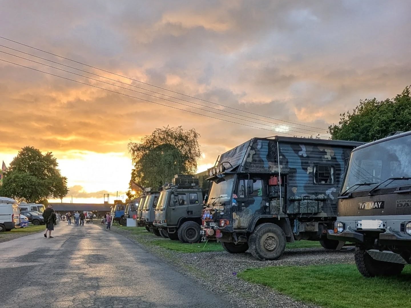 A lineup of custom converted overland trucks at sunset at the Vanlife show