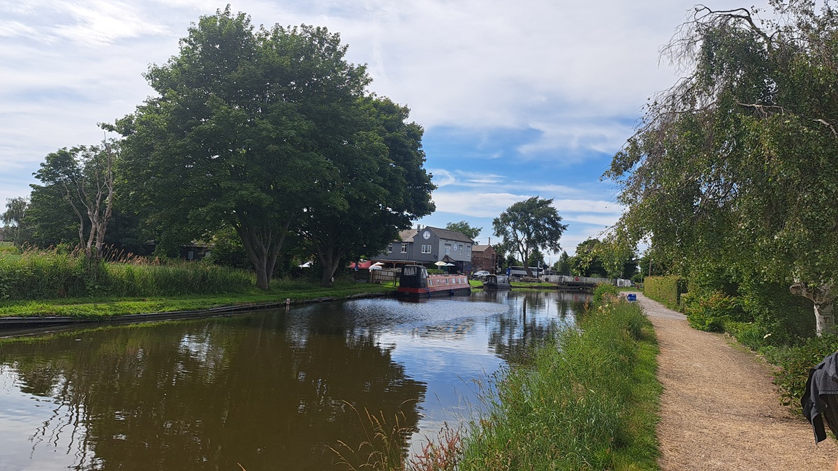 A tranquil canal scene with a canalside pub and trees reflecting in the water