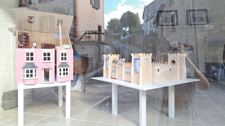Pink dolls' house and small model castle in a shop window