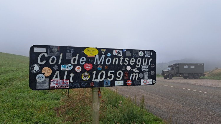 Sign saying Col de Montsegur alt 1059 m with The Beast shrounded in mist in the background